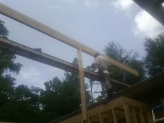 Carpenter setting a ridge beam over a new addition frame — Ice Dam Removal by Roofing Brothers in Basco