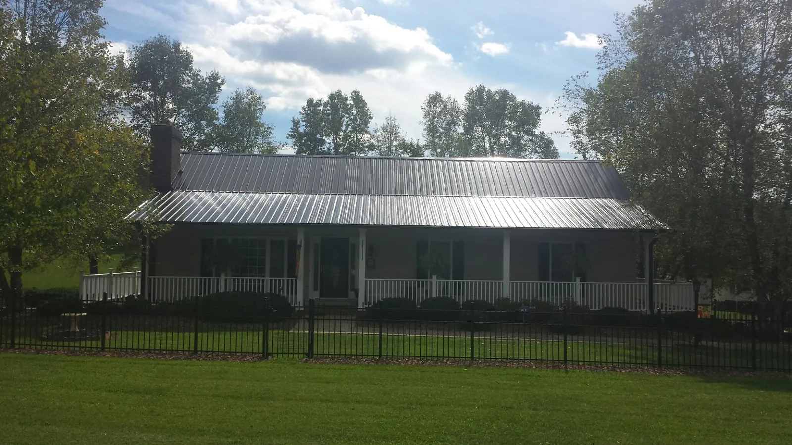 Gray metal roof on a brick ranch with a full width front porch — Gutter Guard Installation work by our crew in Basco