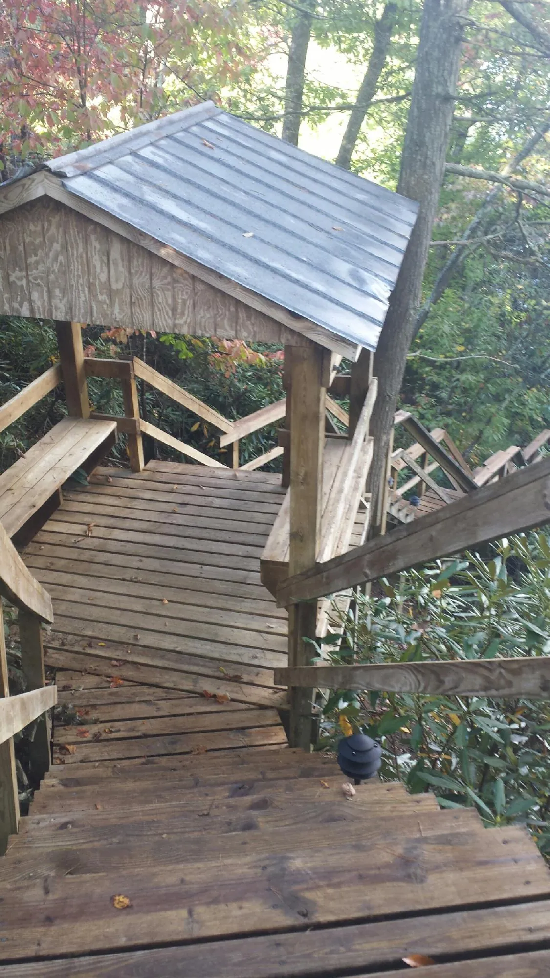 Metal roofed shelter over wooden steps on a wooded walkway — Skylight Repair & Installation work by our crew in Basco