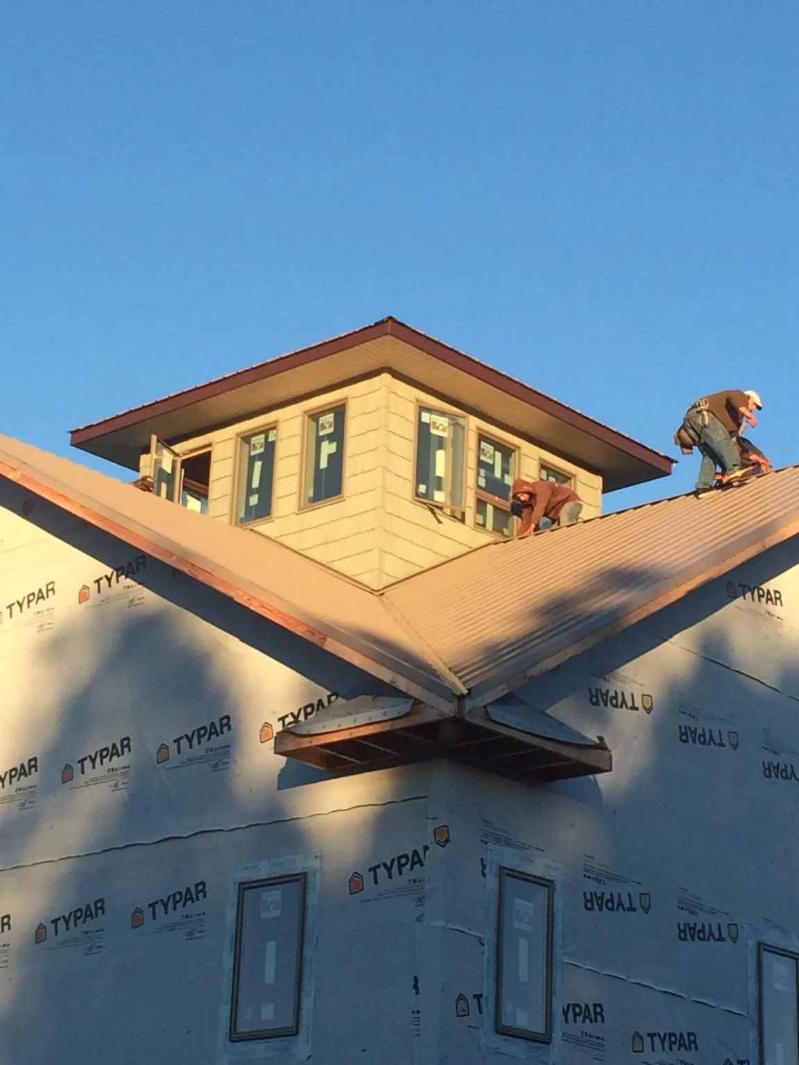 Roofers working around a rooftop cupola on a new metal roof at sunset — Roof Waterproofing in Basco by Roofing Brothers